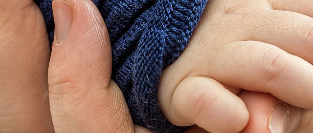 Babyhand umschließt alte Hand – Symbol für Verbundenheit zwischen Generationen